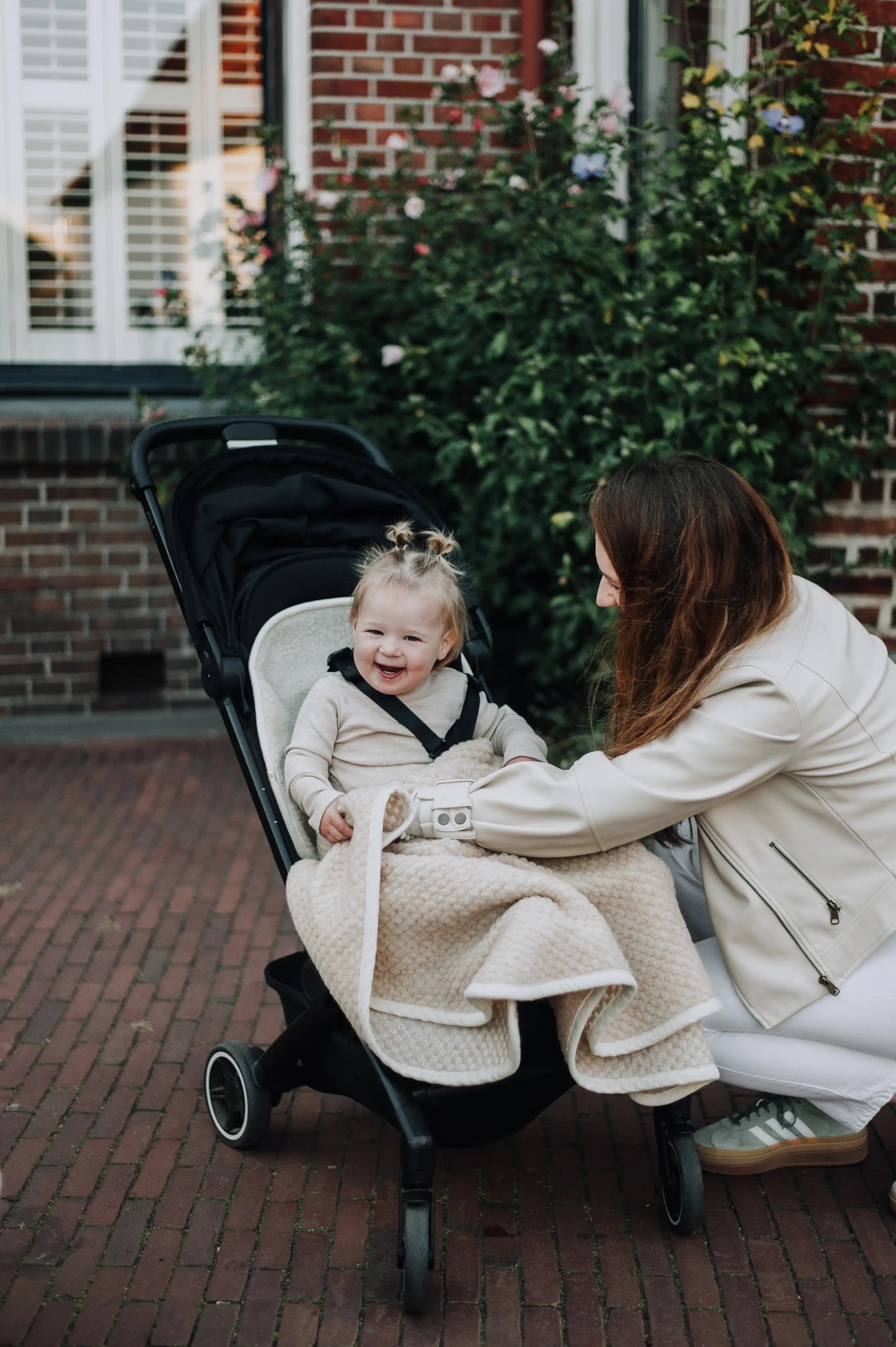 Moeder met blije baby onder wollen boucle deken