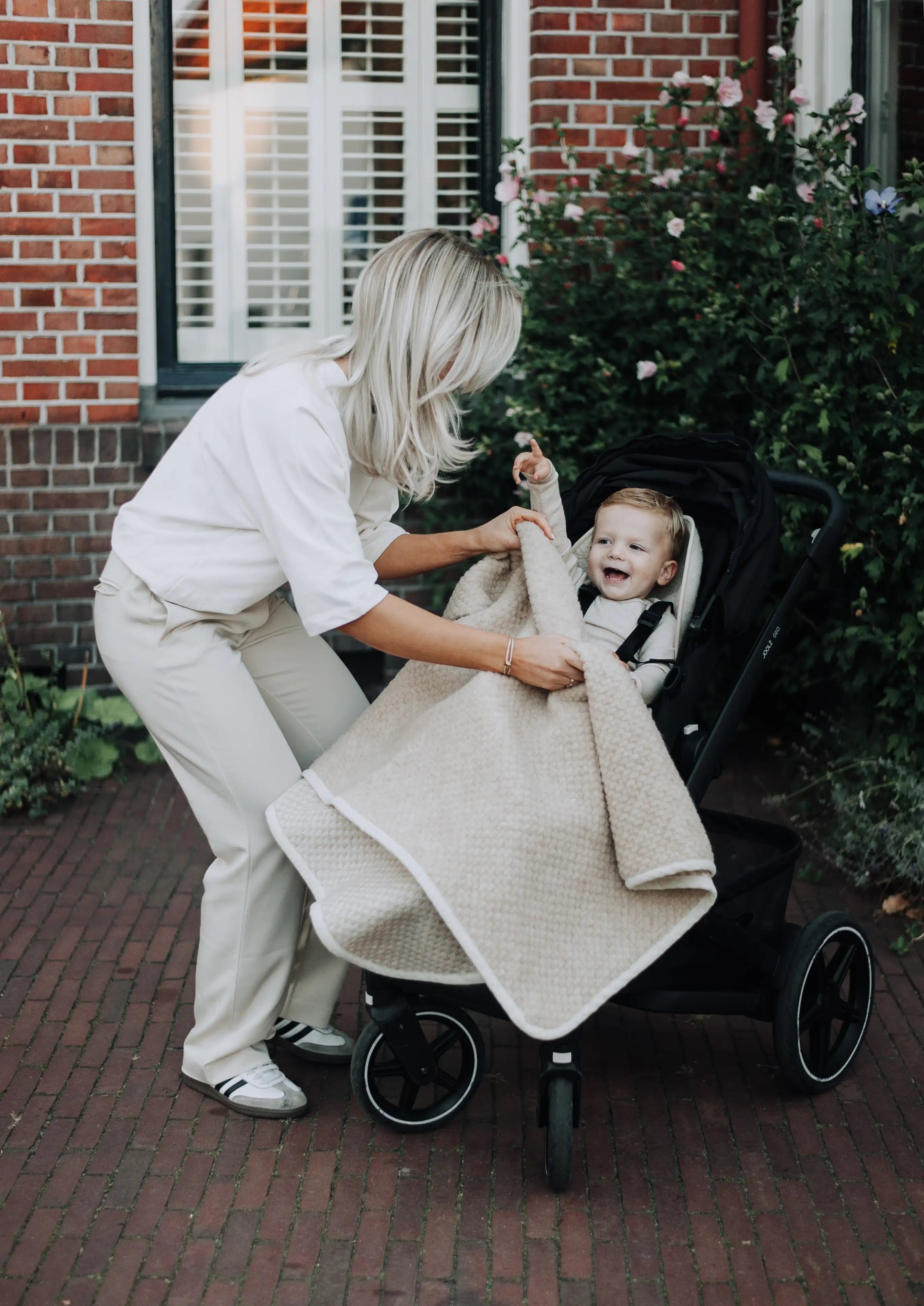 Moeder die blij baby toedekt onder een wolle boucle deken