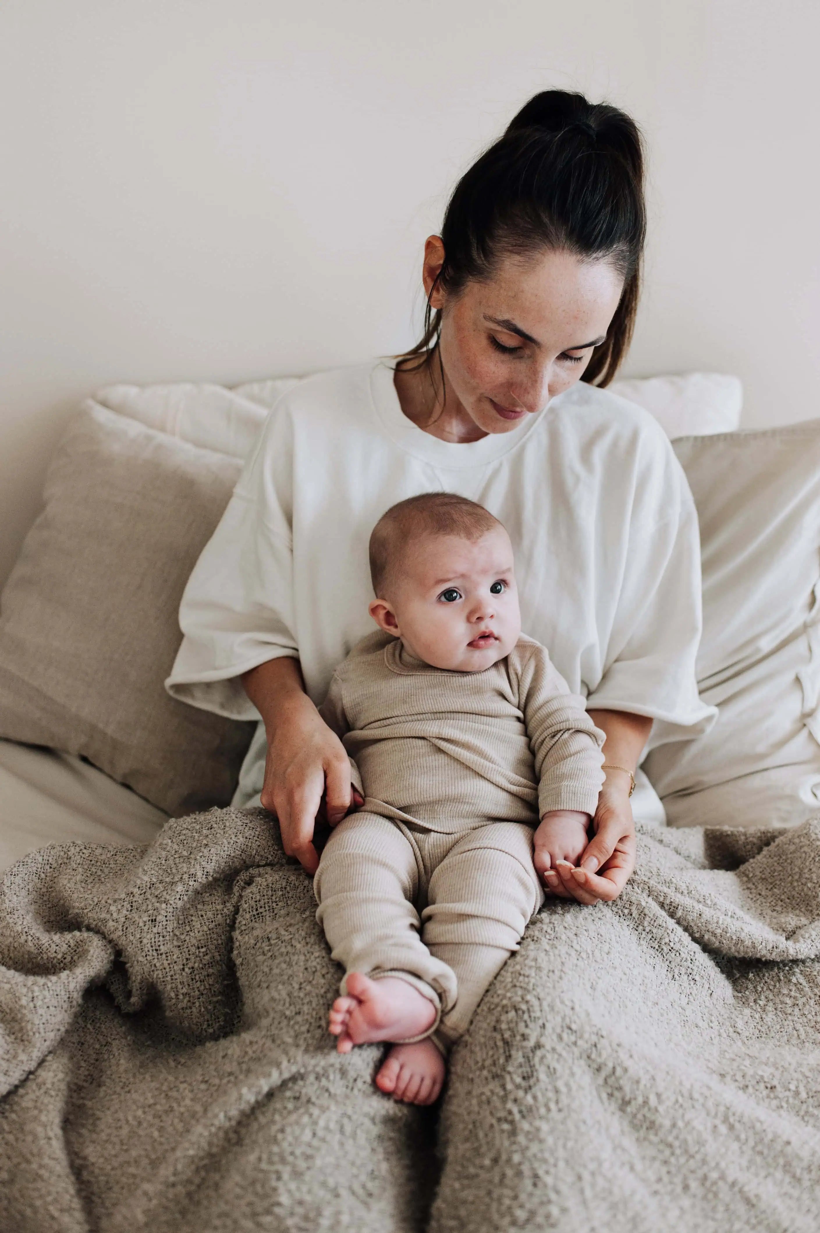 Moeder met baby op schoot die een wollen pyjama aan heeft