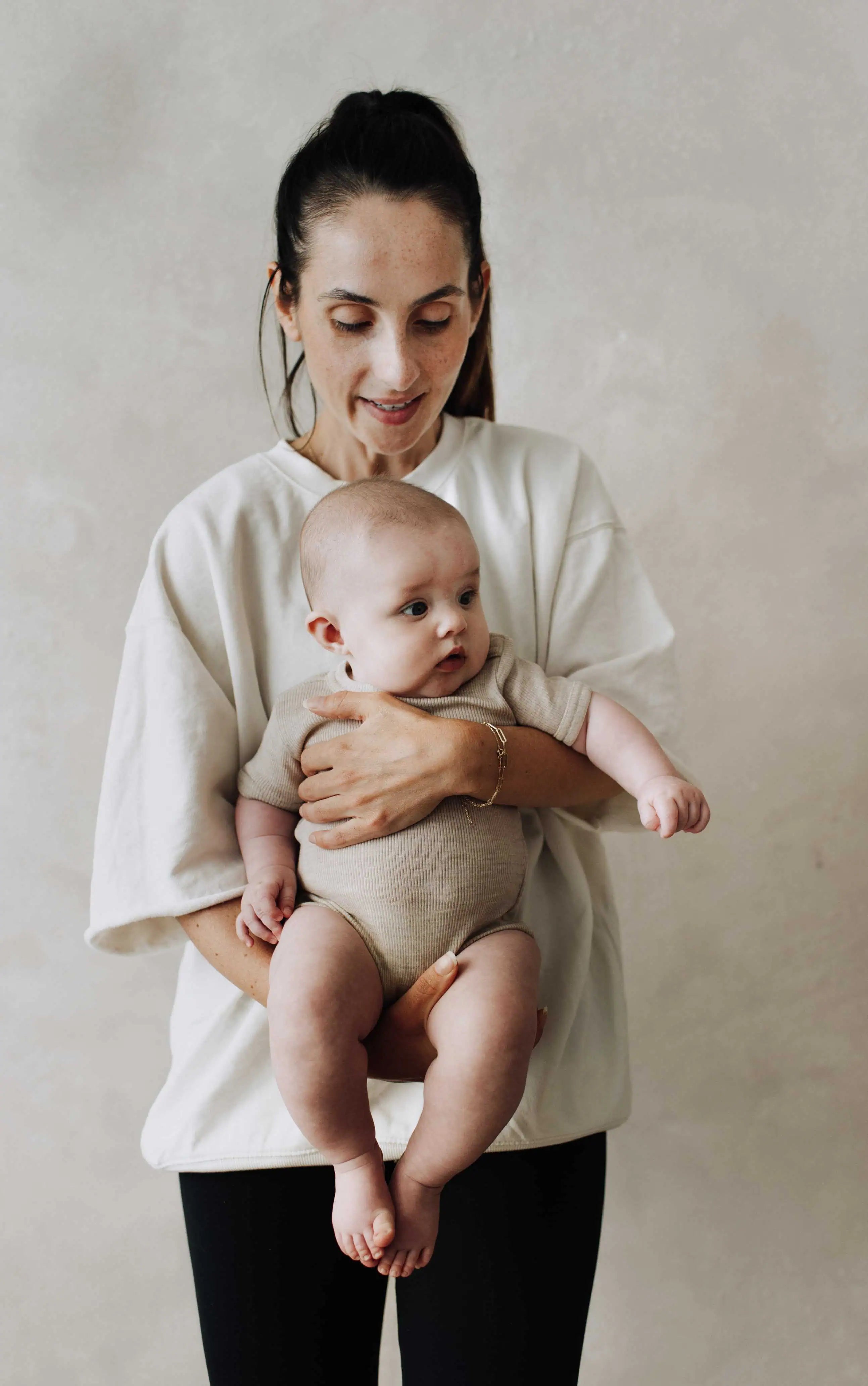 Moeder met zwart haar die baby optilt waarvan de foto van voren geschoten is