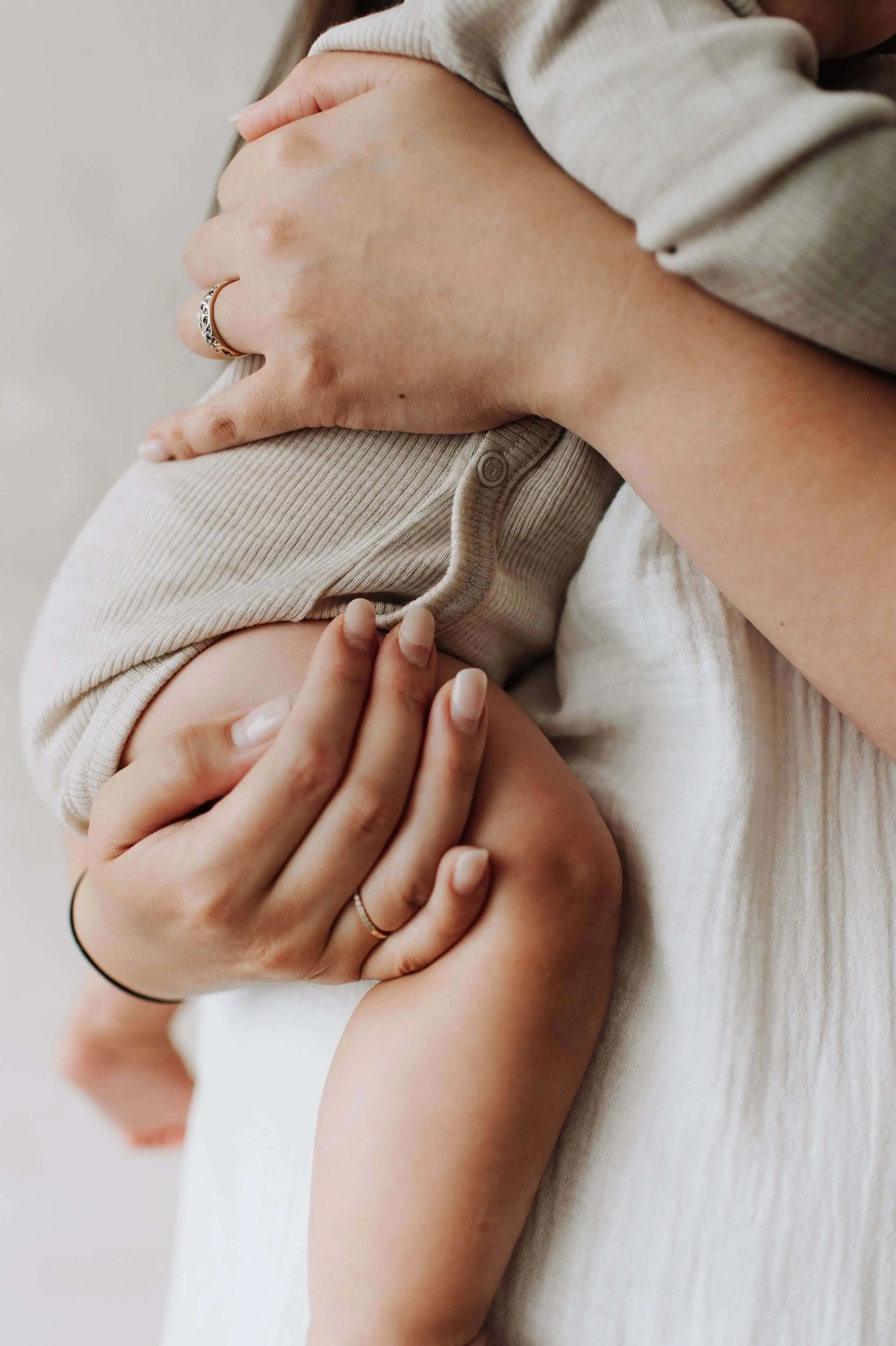 Baby in een wollen overslagromper die opgetild is door zijn moeder